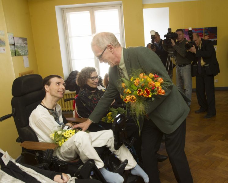 ANDEKAS KUNSTNIK: Jalaga maaliv Meelis Luks saab riigikogu esimehelt Eiki Nestorilt tänukimbu. (Arno Saar)